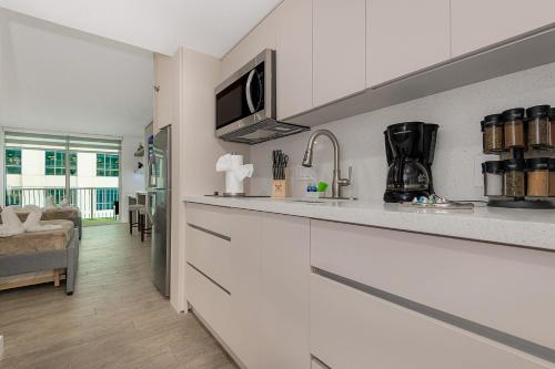 a kitchen with white cabinets and a counter top at High Rise Brickell Modern Studio in Miami