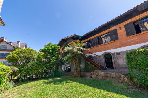 a house with a palm tree in the yard at Casa Tissot- 5 Quartos no Centro de Gramado in Gramado