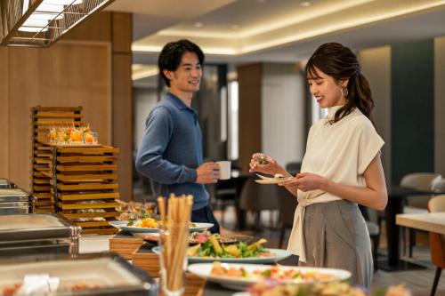 a man and a woman standing in front of a buffet at DoubleTree by Hilton Osaka Castle in Osaka