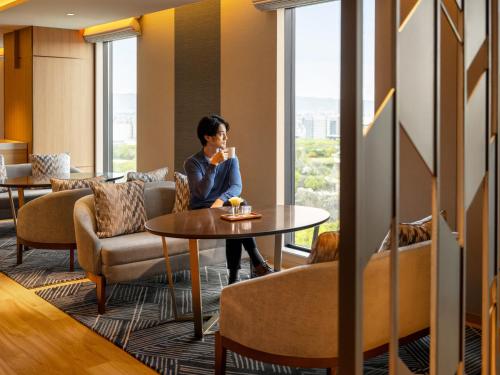 a woman sitting at a table in a room with a window at DoubleTree by Hilton Osaka Castle in Osaka