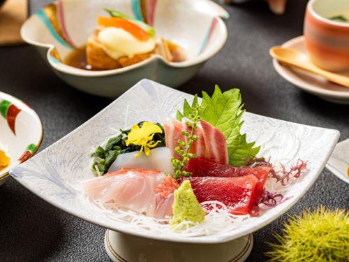 a plate of sushi on a table with other dishes at 公共の宿伊豆まつざき荘 in Matsuzaki