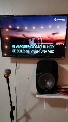 a television on a wall with a microphone on a shelf at Trinitarias House Piscina karaoke Bar wifi in Salinas
