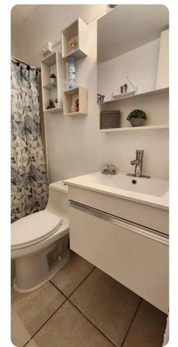 a white bathroom with a toilet and a sink at Trinitarias House Piscina karaoke Bar wifi in Salinas