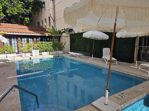 a large swimming pool with an umbrella and chairs at Bellio in Sobe in Miami Beach