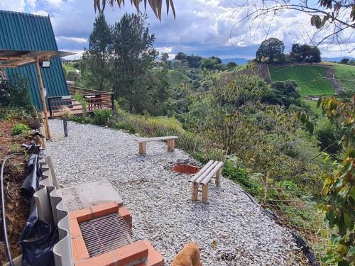 a patio with two benches and a television on a hill at Cabaña Starka & Jacuzzi in Marinilla