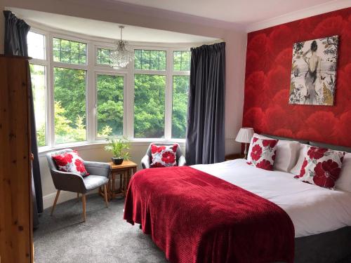 Schlafzimmer mit einem Bett mit einem roten Kopfteil und Fenstern in der Unterkunft The Russell in Scarborough