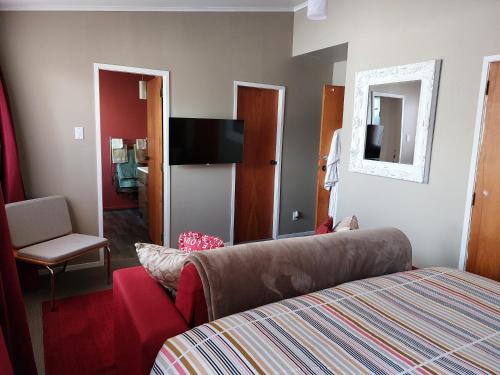 a bedroom with a bed and a chair and a television at Bed and Breakfast Happy Home Taupo Accommodation in Taupo