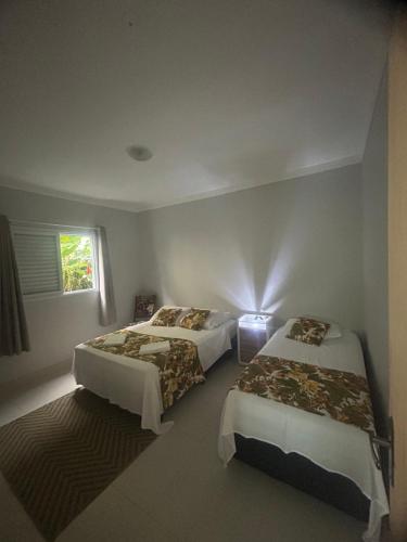 a bedroom with two beds and a window at Residencial Camburyá in Camburi
