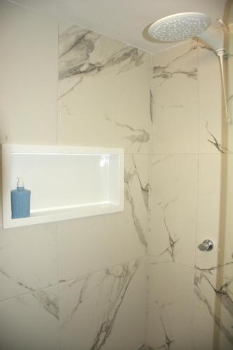 a bathroom with a shower with white marble walls at Araça flat 308 - Lateral Vista Jardim in Natal