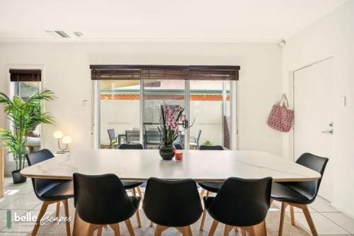 a dining room with a white table and chairs at 3 BR Townhouse Near Airport-City-Beach in Thebarton