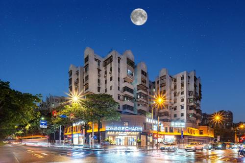 a large building on a city street at night with a moon at Echarm Hotel Guangzhou Baiyun Station Julong Metro Station in Guangzhou