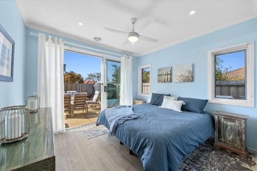 a bedroom with blue walls and a bed with blue sheets at Serenity Nook Cottage in Point Lonsdale