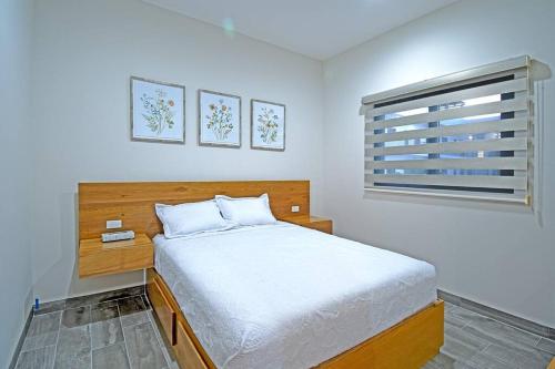 a white bedroom with a bed and a window at Encantador departamento en el corazón de La Paz in La Paz