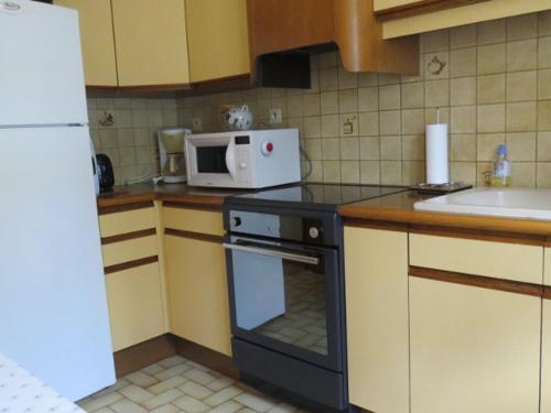 une cuisine avec une cuisinière et un micro-ondes dans l'établissement Charmant 2 Pièces, Balcon, Wi-Fi, Proche Pistes, Chantemerle - FR-1-762-9, à Saint-Chaffrey