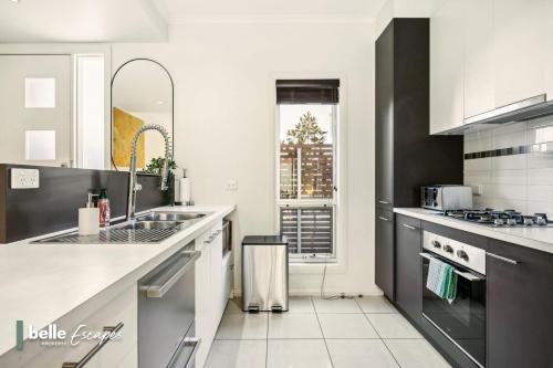 a white kitchen with a sink and a stove at 3 BR Townhouse Near Airport-City-Beach in Thebarton