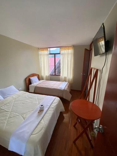 a bedroom with two beds and a table and a window at LagunaNegra Oxapampa in Palmira