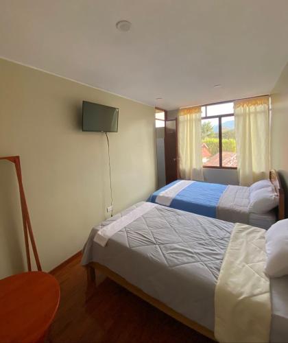 a bedroom with two beds and a tv on the wall at LagunaNegra Oxapampa in Palmira