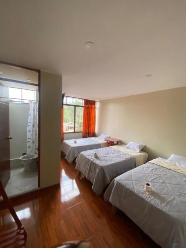 a room with two beds and a bathroom with a shower at LagunaNegra Oxapampa in Palmira