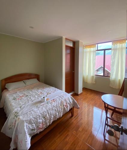 a bedroom with a bed and a table and a window at LagunaNegra Oxapampa in Palmira