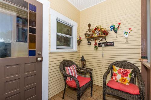 a porch with two wicker chairs and a door at Mistletoe House in Fredericksburg