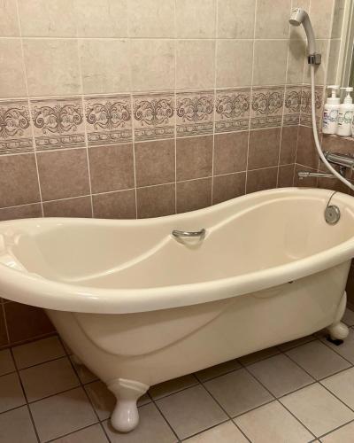 a white bath tub in a tiled bathroom at Asahi House in Hiyakon