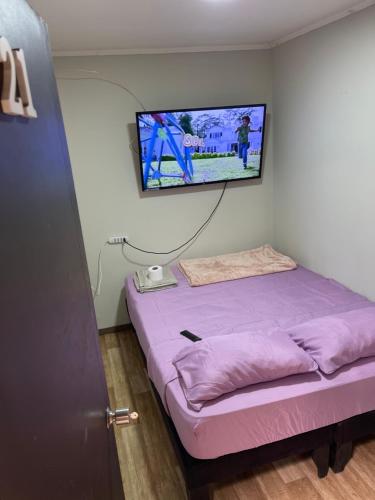 Habitación con cama y TV en la pared. en Hostal Low Cost, en Santiago