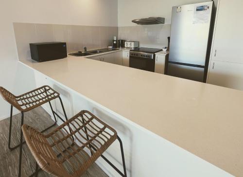 a kitchen with two chairs and a counter and a refrigerator at The Noosa Apartments in Noosa Heads