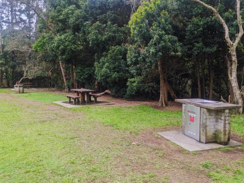a park with two benches and a picnic table at Charlesworth Bay Beach Resort in Coffs Harbour