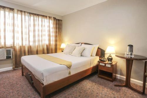 a hotel room with a large bed and a table at Holiday Plaza Hotel - Cebu in Cebu City