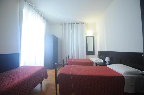 una stanza con tre letti con lenzuola rosse e una finestra di Hotel Beauty a Roma