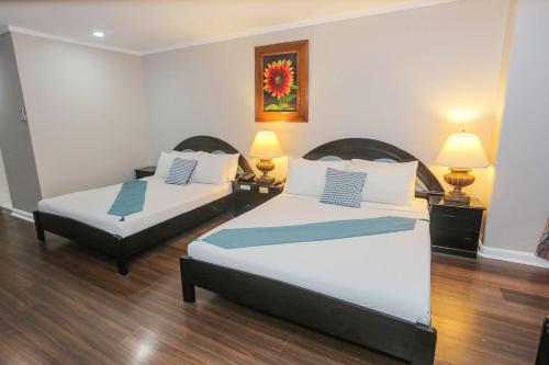 two beds in a hotel room with two lamps at Holiday Plaza Hotel - Cebu in Cebu City