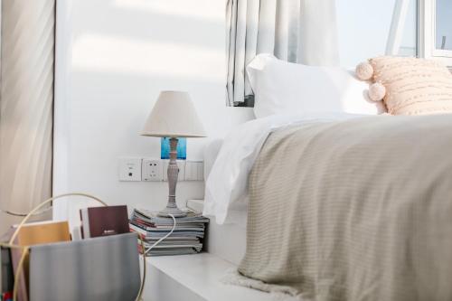 a bedroom with a bed with a lamp and books at Shanghai ruochu designer Guesthouse上海若初设计师民宿--近上海浦东国际机场及迪士尼 in Shanghai
