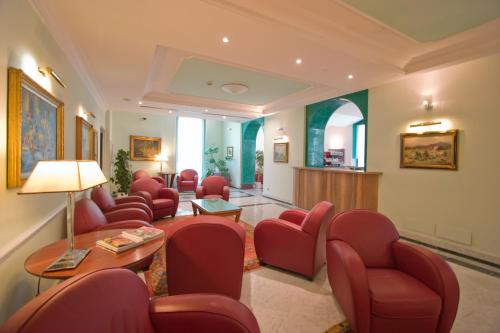 a waiting room with red chairs and a table at Ateneo Garden Palace in Rome