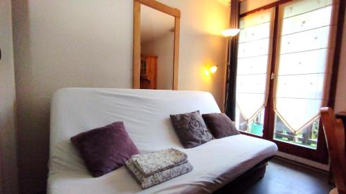 - un canapé blanc avec trois oreillers à côté d'une fenêtre dans l'établissement La Dolce Vita Studio 4 personnes, à Habère-Poche