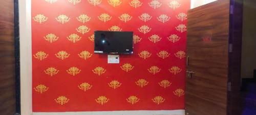 a room with a red wall with a tv on it at Anant home stay in Ujjain