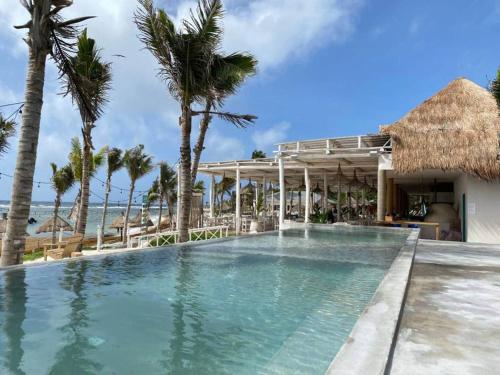 a swimming pool at a resort with palm trees at Departamento 5, Tulum Country Home, con Muelle de Pesca, Club de Playa, Alberca, Cenote y Campo de Golf, Contrata Day Pass Bahia Principe in Tulum
