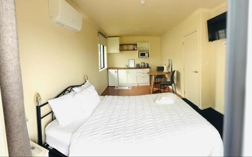 ルアカカにあるLogies Lodgeの小さなベッドルーム(白いベッド1台付)、キッチンが備わります。