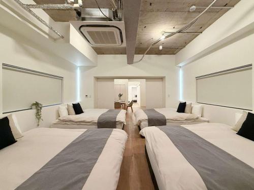 a room with four beds in it with a tv at b hotel NaouBLD - Central Hatchobori 2 Bedroom Apartment for 10 Guests in Hiroshima