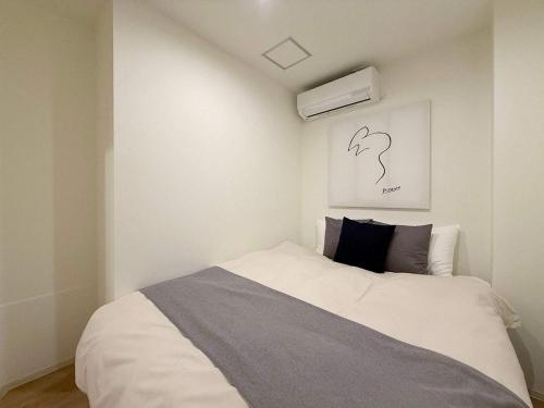 a bedroom with a bed and a painting on the wall at b hotel NaouBLD - Central Hatchobori 2 Bedroom Apartment for 10 Guests in Hiroshima
