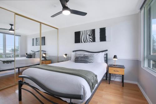 Seascape Sanctuary - Palm Beach Resort-style Bliss في غولد كوست: غرفة نوم بها سرير ومروحة سقف