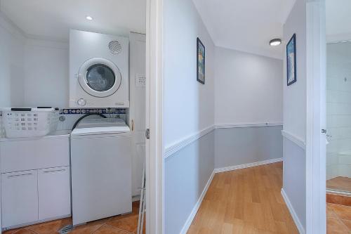 Seascape Sanctuary - Palm Beach Resort-style Bliss في غولد كوست: غرفة غسيل بيضاء مع غسالة ومجفف