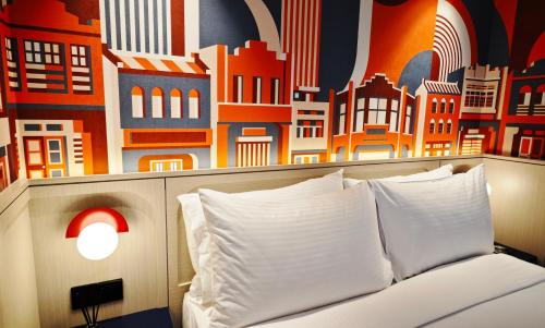 a bed with white pillows in front of a mural at lyf Georgetown Penang in George Town