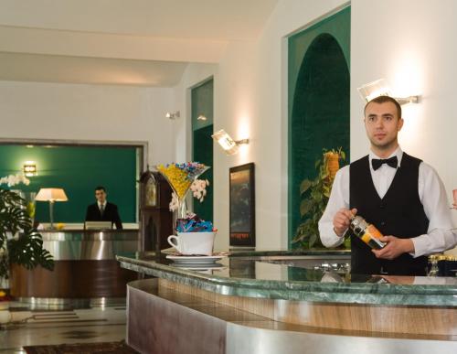 a man in a tuxedo holding a bottle of wine at Ateneo Garden Palace in Rome