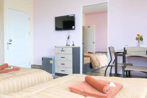 a room with two beds and a table with a television at The Wish Hotel in Chachoengsao