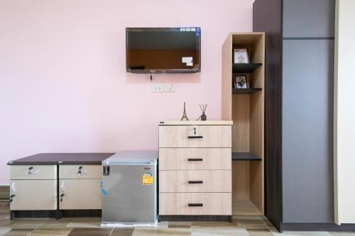 a kitchen with a refrigerator and a tv on the wall at The Wish Hotel in Chachoengsao