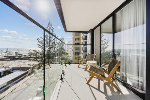 a balcony with two chairs and glass windows at The Shores Surfers Paradise Apartments in Gold Coast