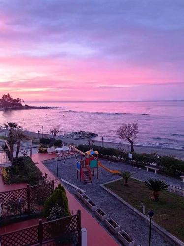 a playground next to the ocean at sunset at Appartamento in Residence La Vela in Palizzi Marina