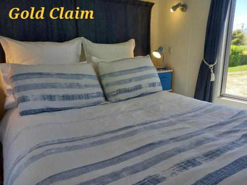 a bed with a blue and white blanket and a window at Charleston Goldfields Accommodation in Charleston