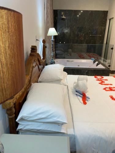 a bedroom with a bed with pillows and a tub at POUSADA CHARLOTTE in Tiradentes