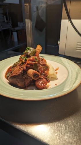 a plate of food with meat and mushrooms on a table at GRAND CENTRAL HOTEL PROSERPINE in Proserpine